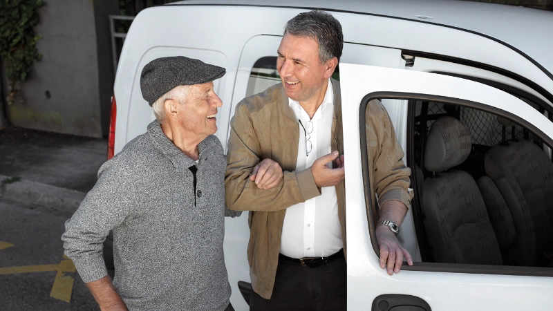 Un homme aide un senior à monter dans la voiture