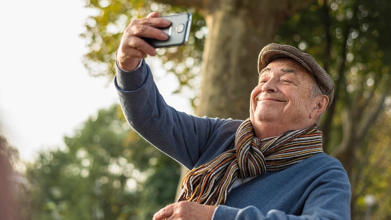 Un senior prend un selfie avec son smartphone.