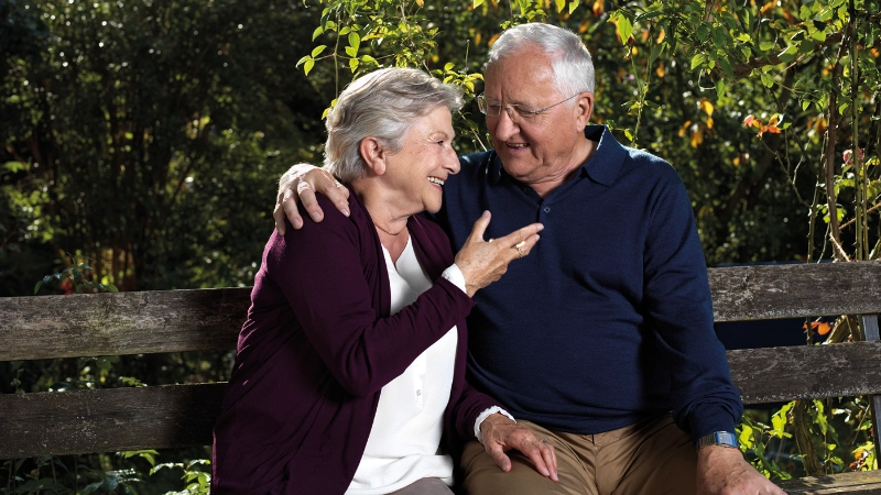 Un couple âgé est assis ensemble sur un banc de parc.