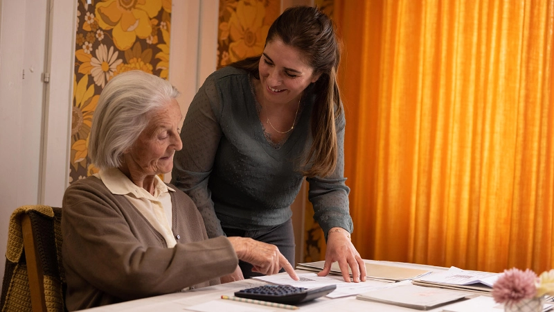 Une femme âgée fait ses comptes.