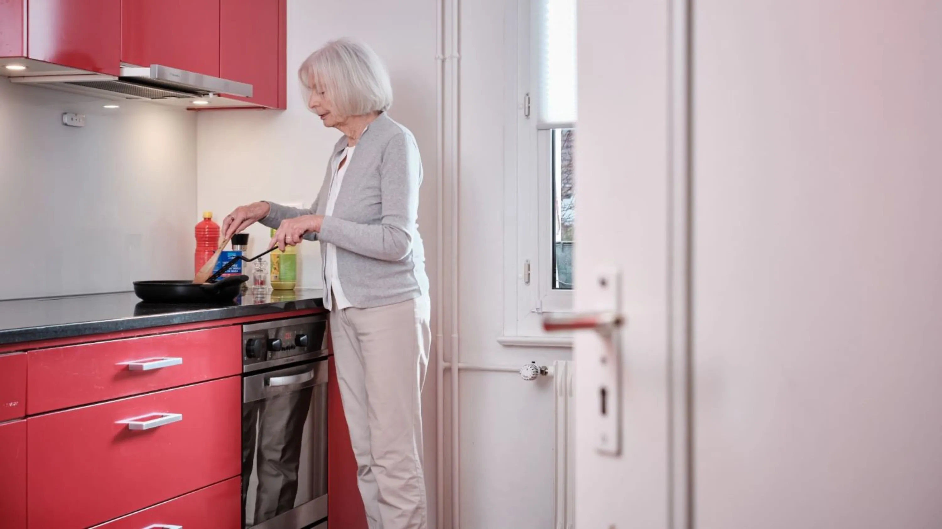 Senioren steht in Küche und kocht mit Pfanne