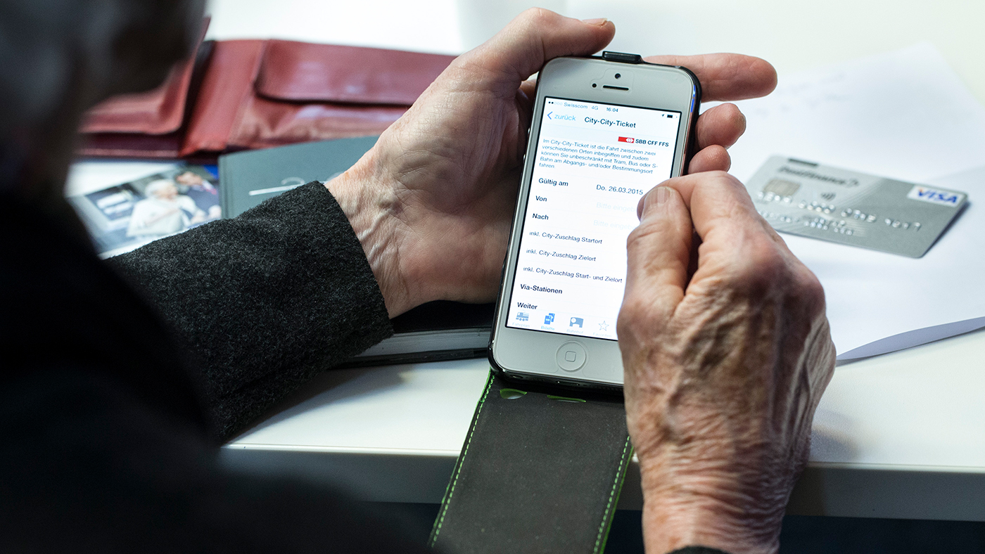 Un senior tient son Ipad entre ses mains et lit.