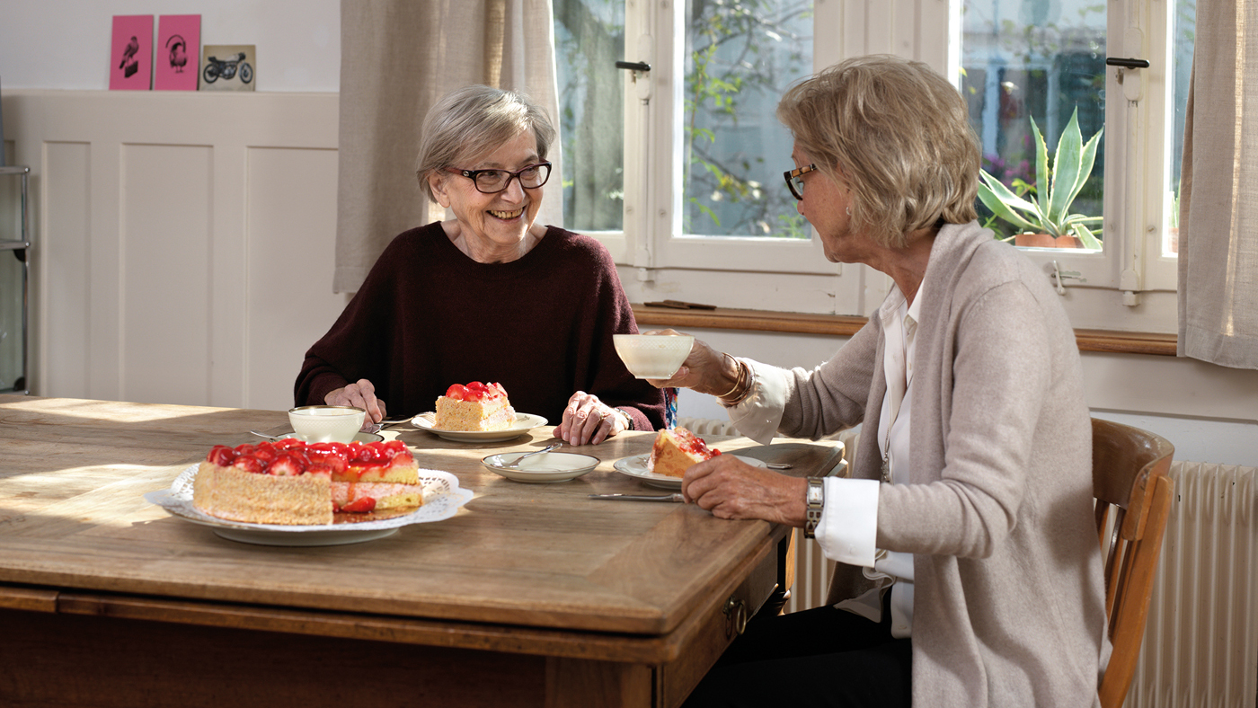 Deux femmes âgées à table autour d'un café et d'un gâteau